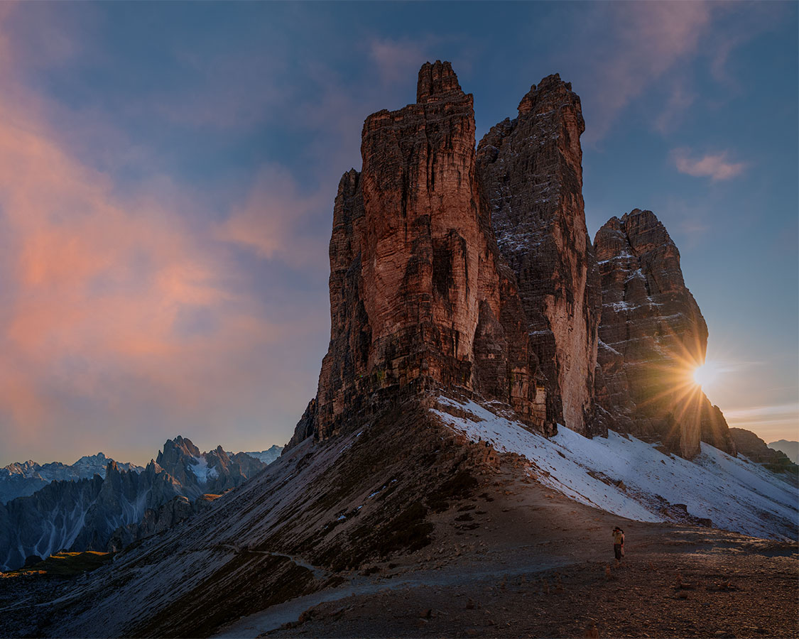 Sunset light on Tre Cime di Lavaredo with a starburst and alpine cliffs in the Dolomites