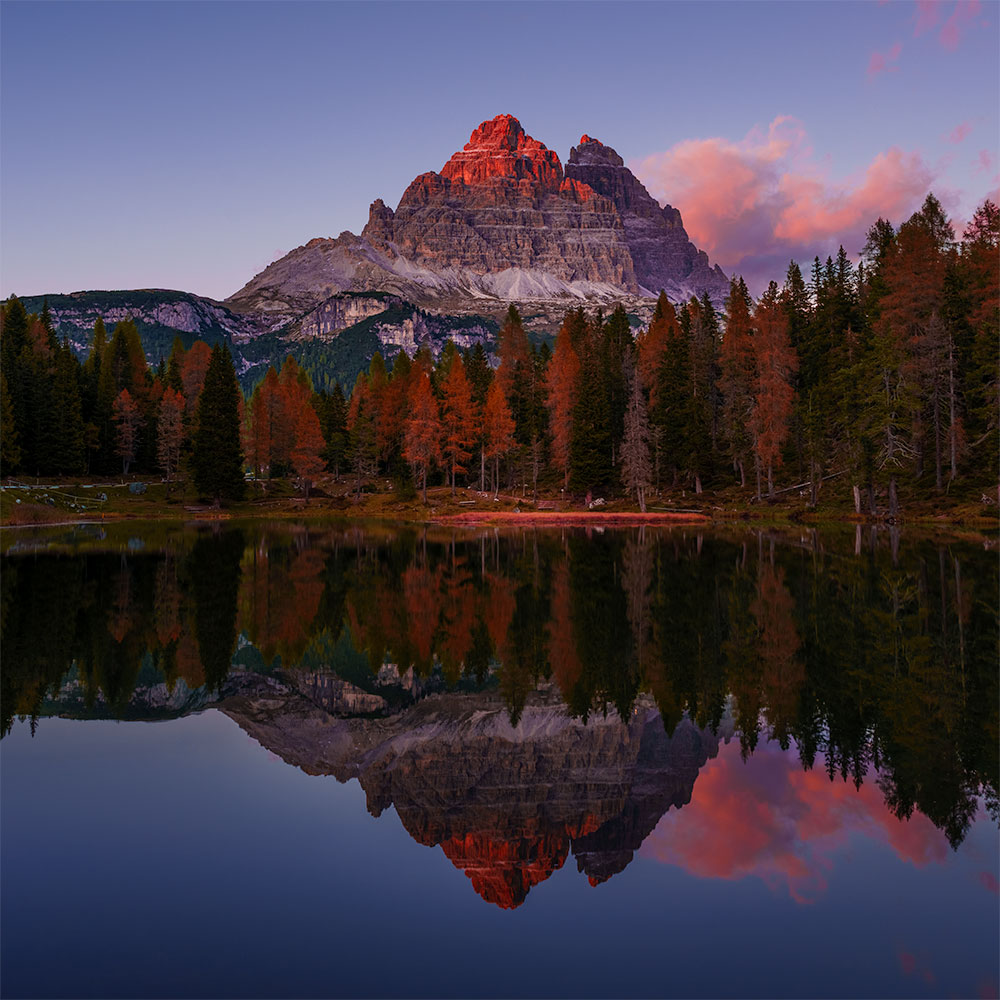 Alpenglow on a mountain peak reflected in Lake Antorno near Tre Cime in the Dolomites